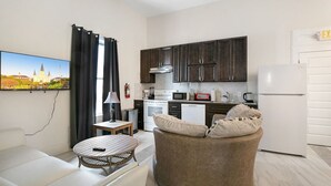 A modern kitchen with dark cabinets, a white refrigerator, and a dining area with a round table and a sofa. - Chic and Roomy Urban Getaway in New Orleans (New Orleans)
