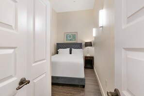 Una habitación de hotel con una cama, una mesita de noche, una lámpara y un cuadro en la pared.