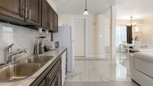 Una cocina moderna con armarios oscuros, lavamanos de acero inoxidable y un refrigerador blanco.