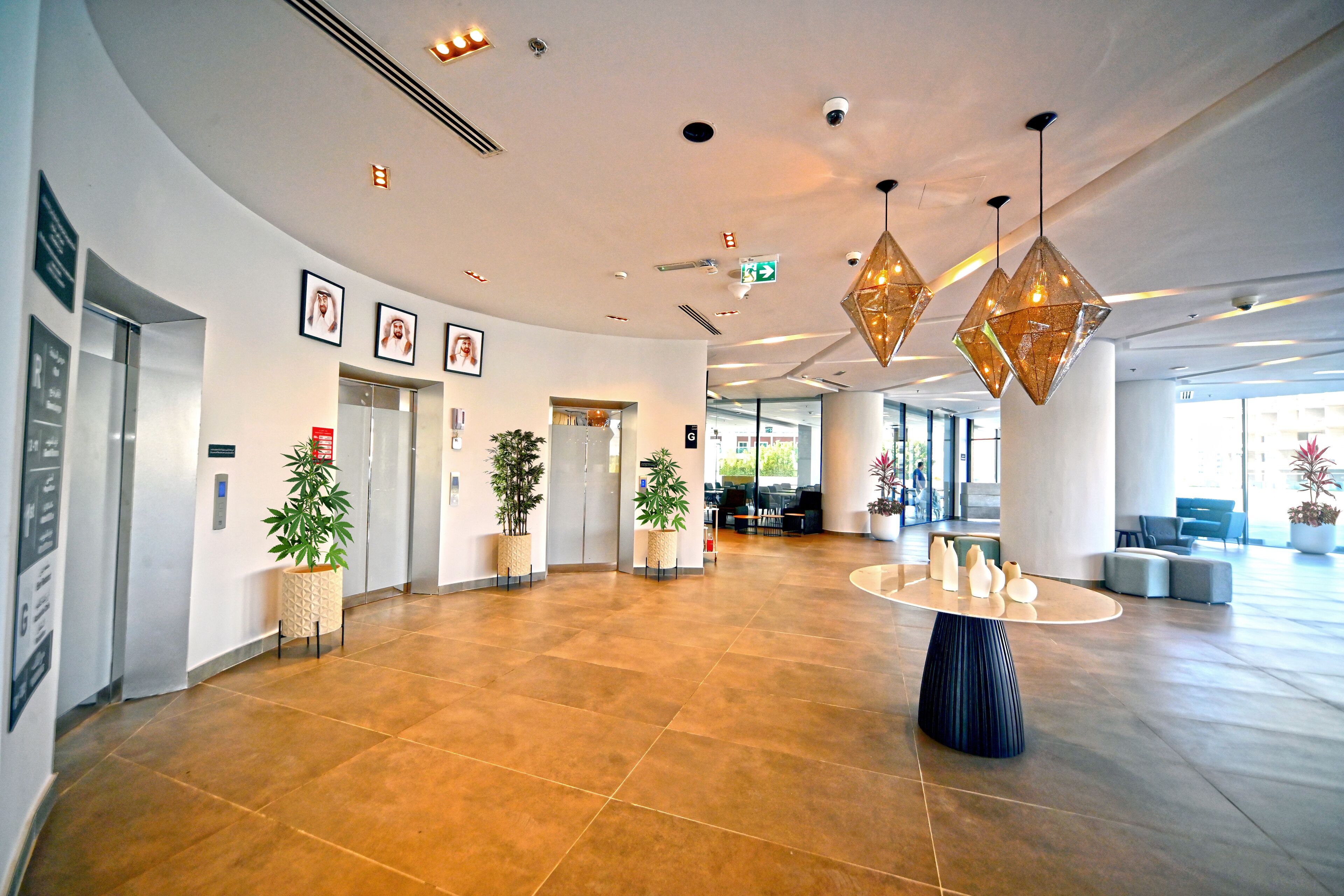 A spacious lobby with a curved ceiling, potted plants, a round table with decorative items, and a seating area with a blue sofa.