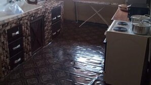 Een kleine keuken met een spoelbak, fornuis en droogrek.