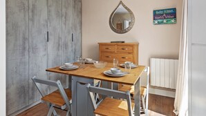 Een eetgedeelte met een houten tafel voor vier personen, een spiegel erboven en een kastje eronder.