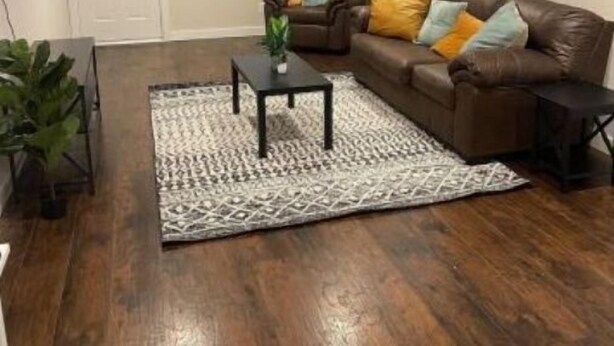 Un salón con un sofá de cuero marrón, una mesa de centro y una alfombra estampada.