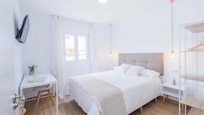 Une chambre à coucher moderne comprenant un lit, des tables de chevet, un bureau, un miroir et une armoire.