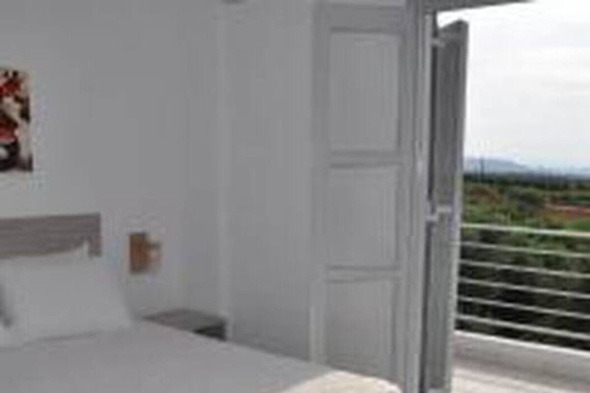 A bedroom with a bed, a nightstand, and a door leading to a balcony.