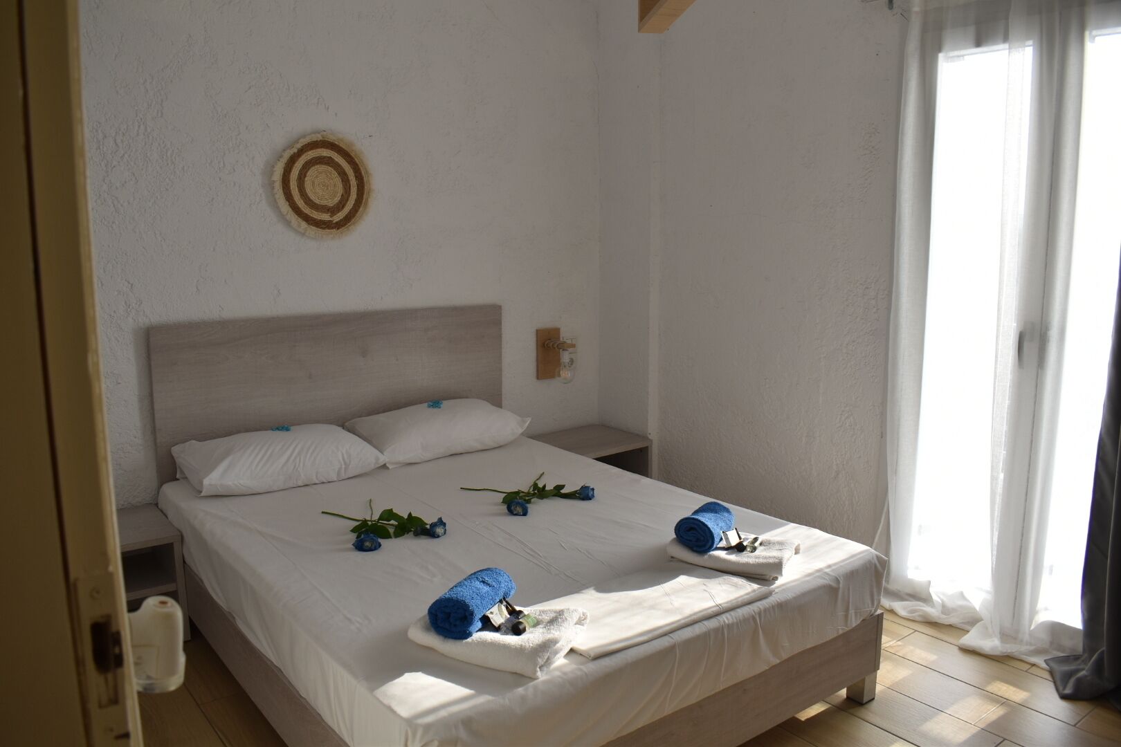 A neatly made bed with white linens, two pillows, and a decorative wall piece.