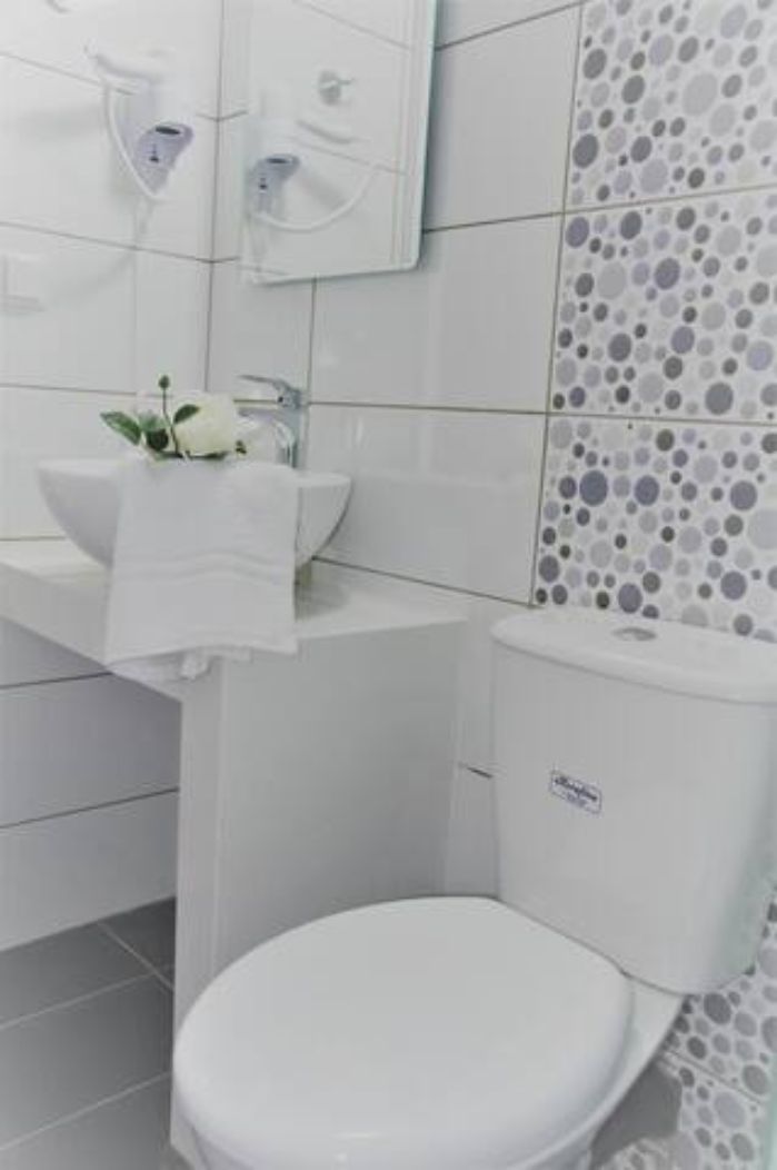 A bathroom with a white sink, mirror, and toilet.