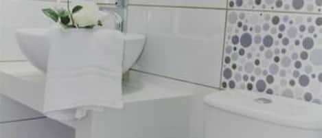 A bathroom with a white sink, mirror, and toilet.