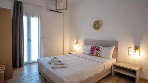 A neatly made bed with a headboard, bedside tables, and a wall-mounted light fixture. - Ble Island (Hersonissos)