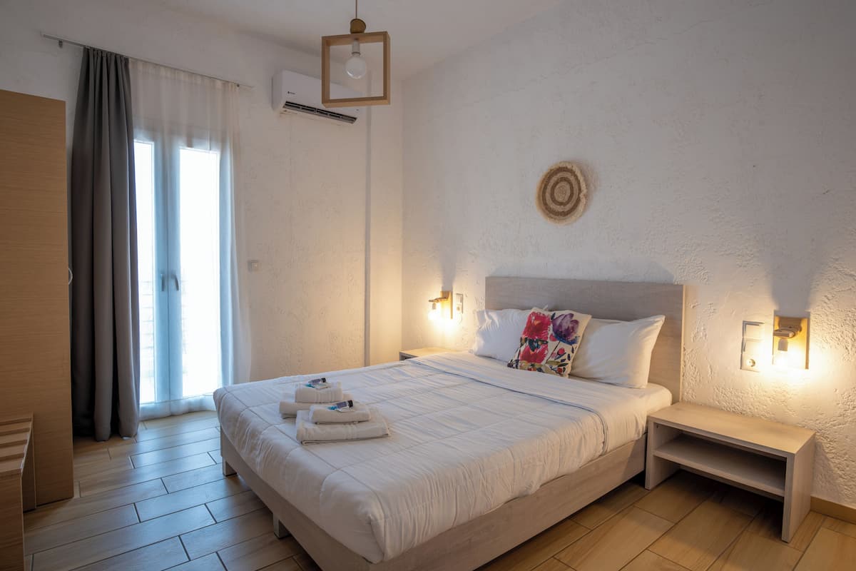 A neatly made bed with a headboard, bedside tables, and a wall-mounted light fixture.