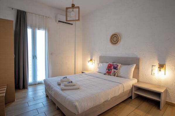A neatly made bed with a headboard, bedside tables, and a wall-mounted light fixture.
