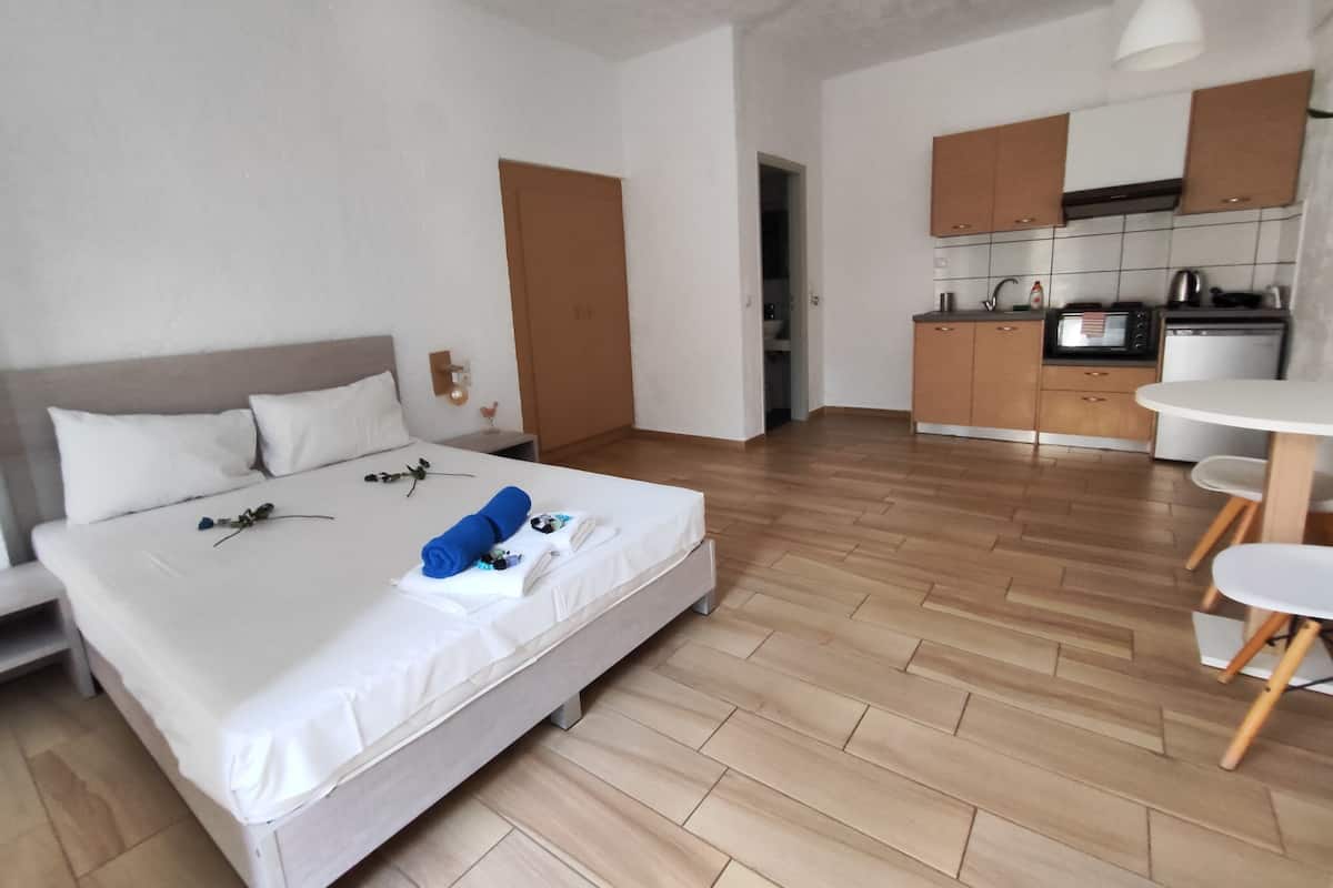 A modern hotel room with a large bed, a small kitchenette, and a dining area.