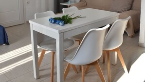 A dining area with a white table and four white chairs, a beige sofa, and two decorative mirrors on the wall. - Ble Island (Hersonissos)