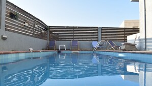 A swimming pool with tiled walls, a wooden fence, and lounge chairs. - Ble Island (Hersonissos)