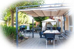 An outdoor patio area with a covered seating area, tables, and chairs. - Hostal La Llave (Aguilar de Campoo)