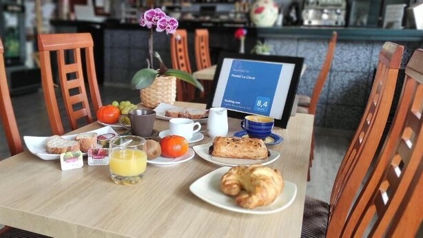 Een ontbijttafel met verschillende soorten eten, een fruitschaal, een koffiekop en een digitaal menubord.