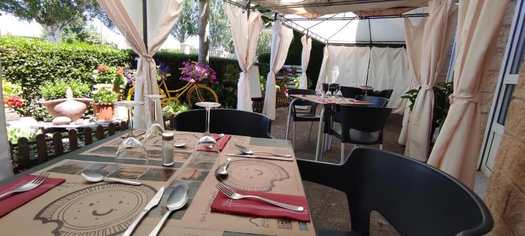 An outdoor dining area with tables set for two, featuring a smiley face placemat.