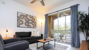 A modern living room with a sofa, a coffee table, and a large window with curtains. - Dream Cozy 3BR Condo - Disney 5 Min, Walk to Pool! (Orlando)