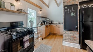 A modern kitchen with wooden beams, a black refrigerator, and a chalkboard with "hola" written on it. - Chic Retreat, 2 Queen Beds, FREE PARKING, Walk to Train (Oak Park)