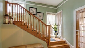 A wooden staircase with a bench at the bottom, a door with a curtain, and a window with a plant. - Chic Retreat, 2 Queen Beds, FREE PARKING, Walk to Train (Oak Park)