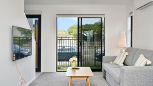 A modern living room with a grey sofa, a wooden coffee table, and a TV mounted on the wall. - Sea Air and Sandy Beach Beautiful 1 bed 1 bath (Christchurch)