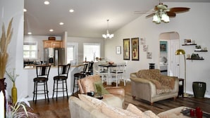 A spacious living area with a dining table, two sofas, and a kitchen in the background.