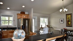 A modern kitchen with a large island, stainless steel appliances, and a dining area with a chandelier.