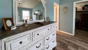 A room with a large white dresser, a mirror, and a light blue wall.