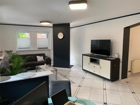 A modern living room with a sofa, coffee table, and a TV on a cabinet.