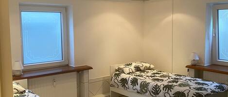 Et soveværelse med to senge, et vindue og en radiator.