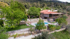A two-story stone house with a red-tiled roof, a swimming pool, and a well-maintained garden. - Calypso Villa with Jacuzzi Pool & Sea View (Dafni)