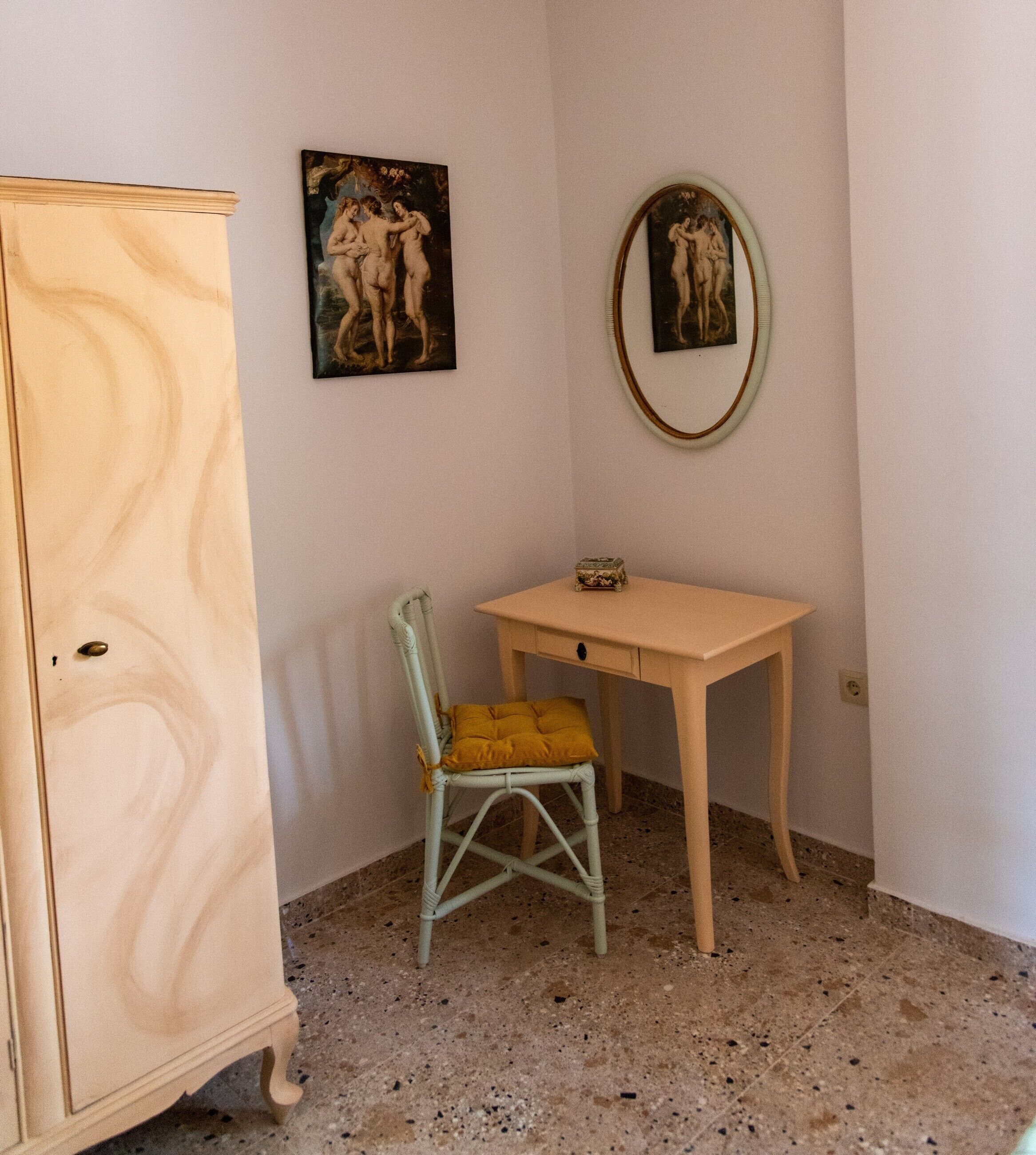 Een kamer met een houten kast, een klein bureau en twee kunstwerken in lijsten aan de muur.