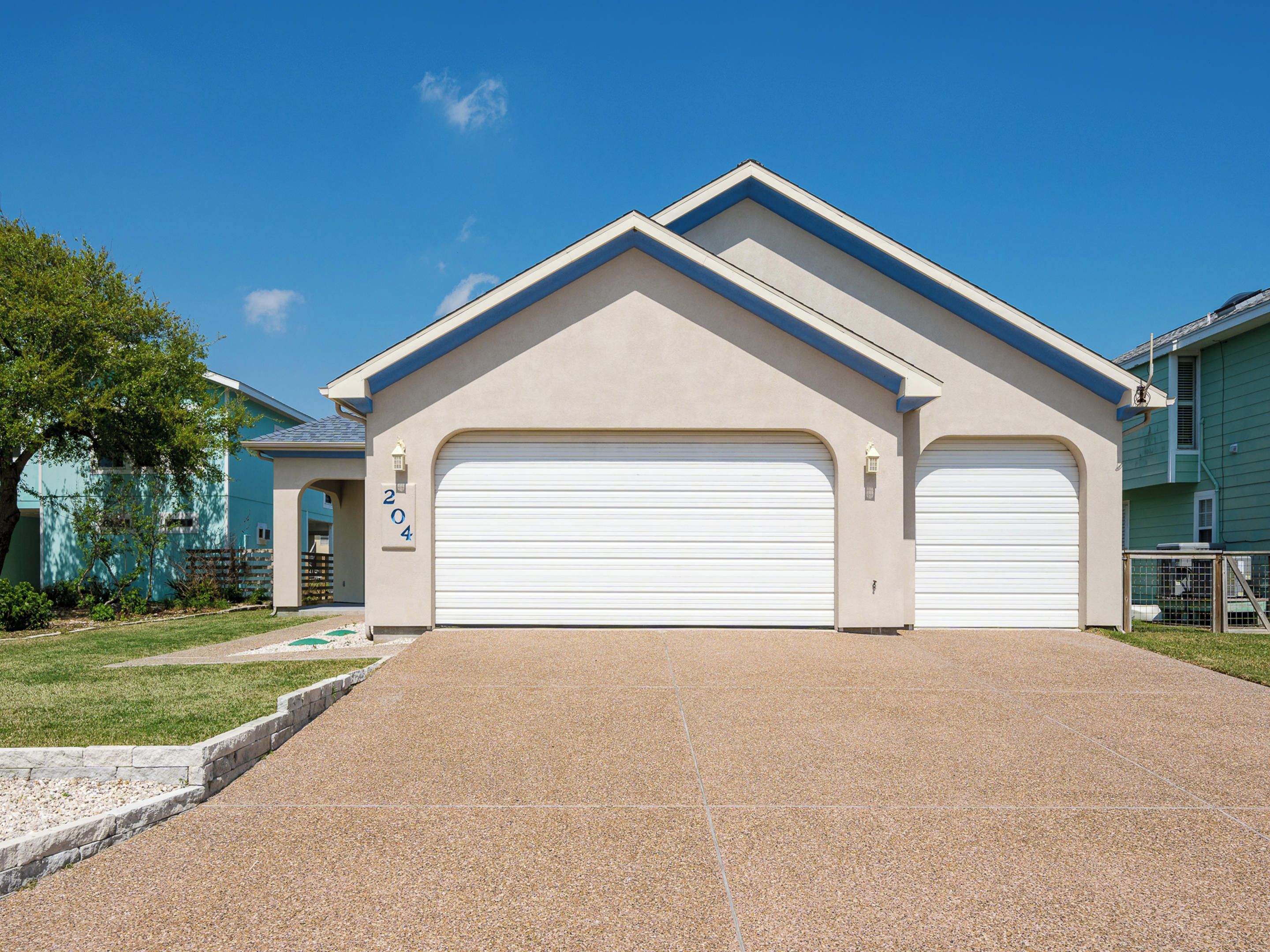 Einbungalow mit Garage, auf der Garagentür die Nummer 204, und einem strahlend blauen Himmel.