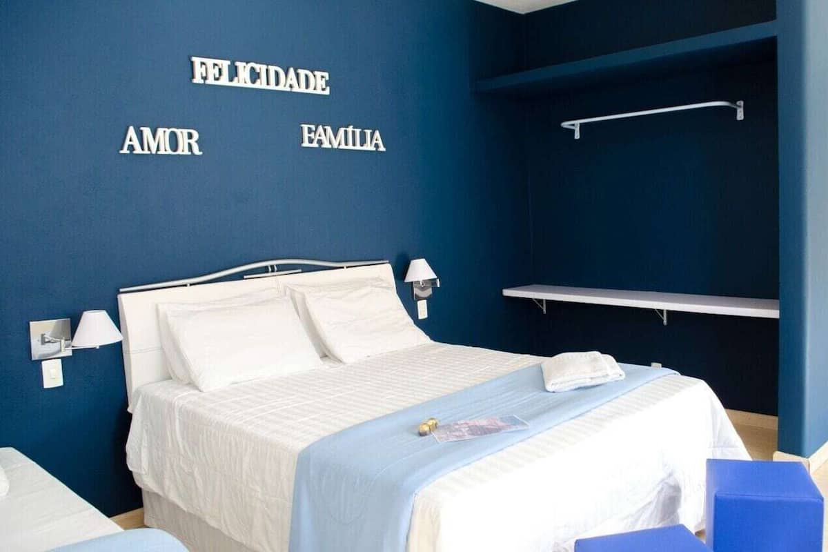 Ein Schlafzimmer mit einem Bett, einem Nachttisch, einer Wandlampe und einem Regal.