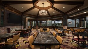 Enjoy meals in a spacious dining area with round and rectangular tables, leather and fabric chairs, and large windows offering views of the outdoors.