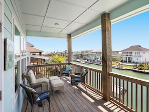 A covered outdoor area with wicker furniture and a view of a marina. - Port Royal Dream by Miss Kitty’s (Aransas Pass)