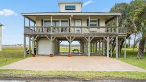 A two-story wooden house with a balcony, a garage, and a clear view of the surrounding landscape.