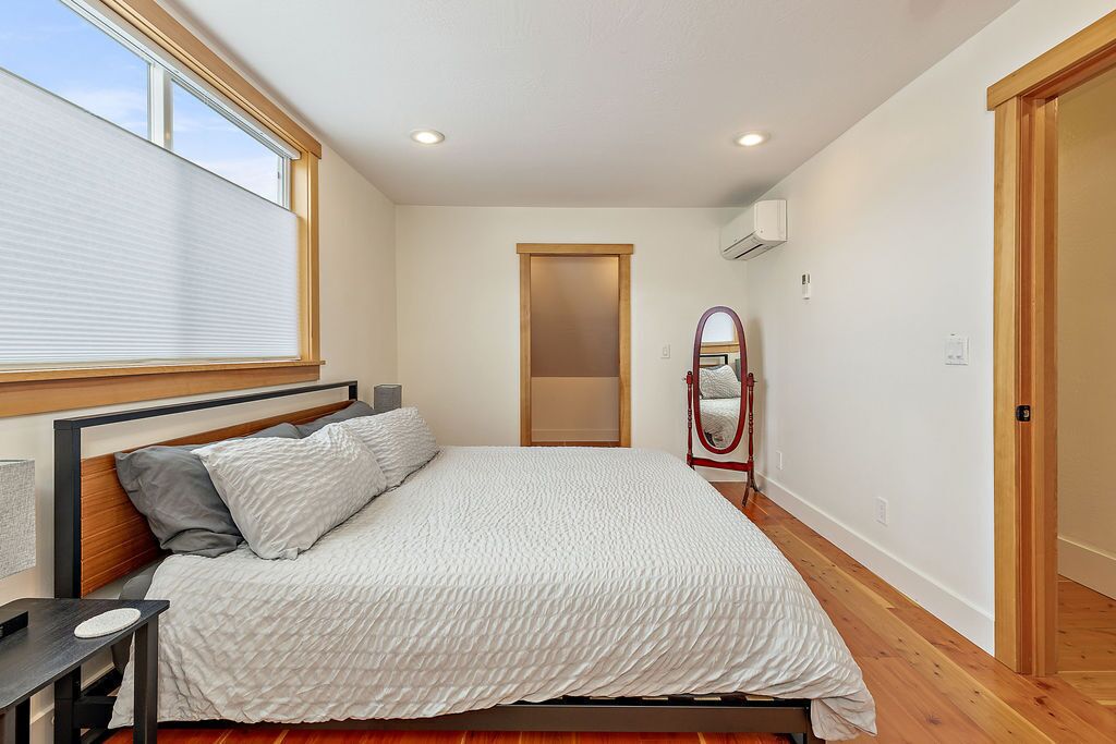 Une chambre à coucher avec un lit, une table de chevet, un miroir et une fenêtre.