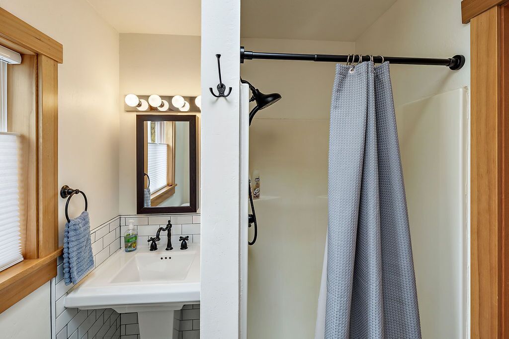 A bathroom with a white sink, mirror, and shower curtain.