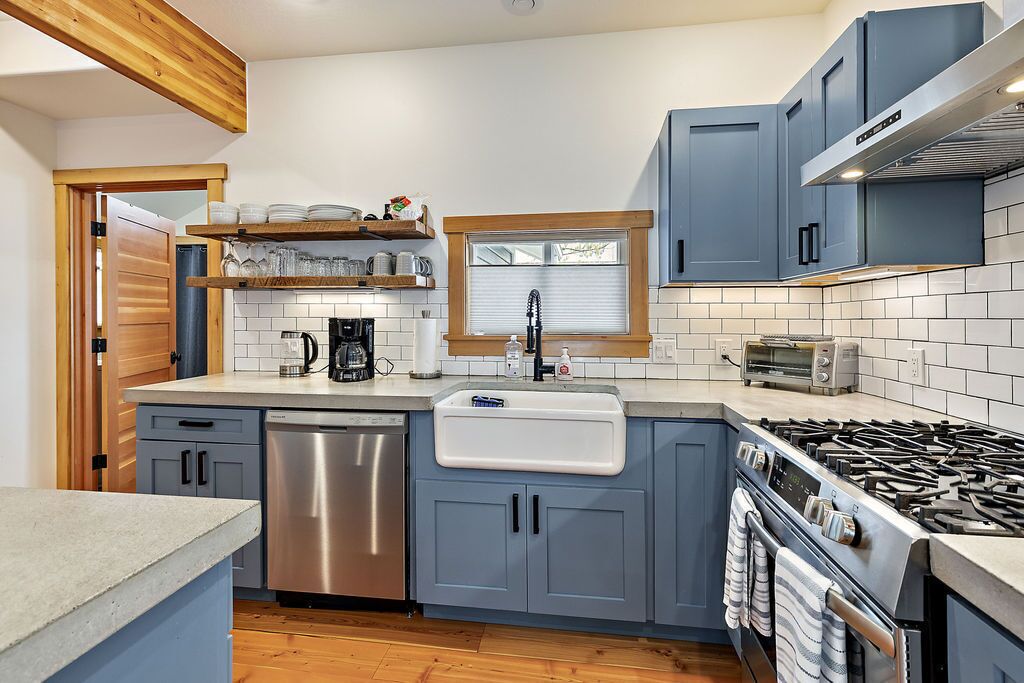 A modern kitchen with grey cabinets, a stainless steel dishwasher, a built-in oven, and a gas stove.