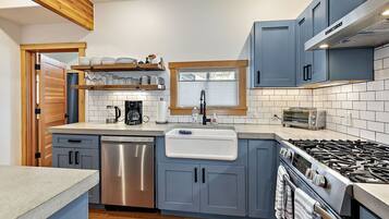 A modern kitchen with grey cabinets, a stainless steel dishwasher, a built-in oven, and a gas stove.