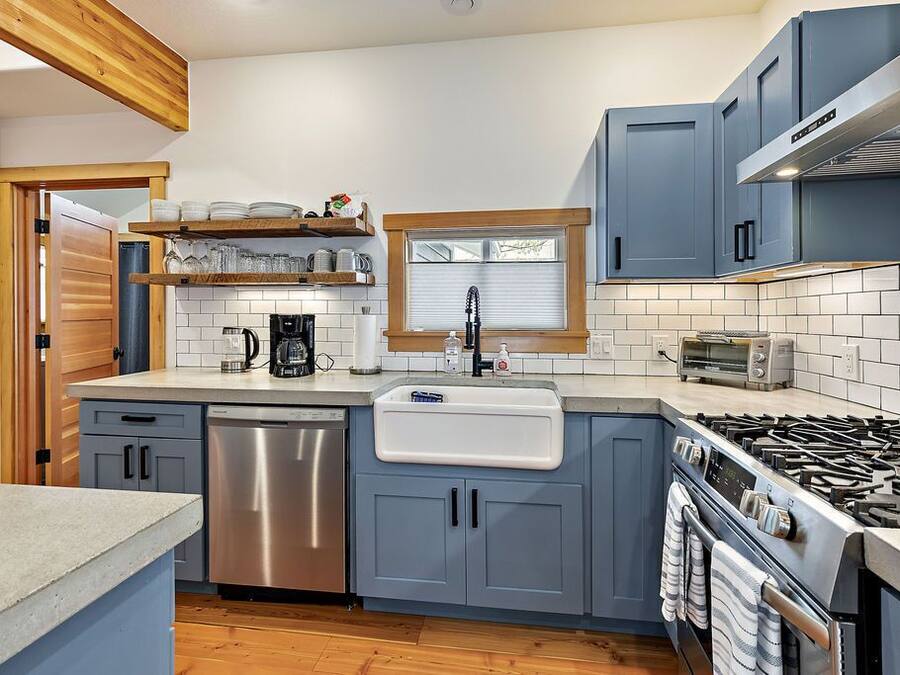 A modern kitchen with grey cabinets, a stainless steel dishwasher, a built-in oven, and a gas stove.
