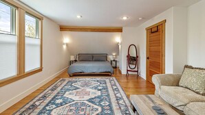 A bedroom with a bed, a wooden floor, a patterned rug, a sofa, and a wardrobe. - The Mountain Ave House by WanderLodges (Ashland)