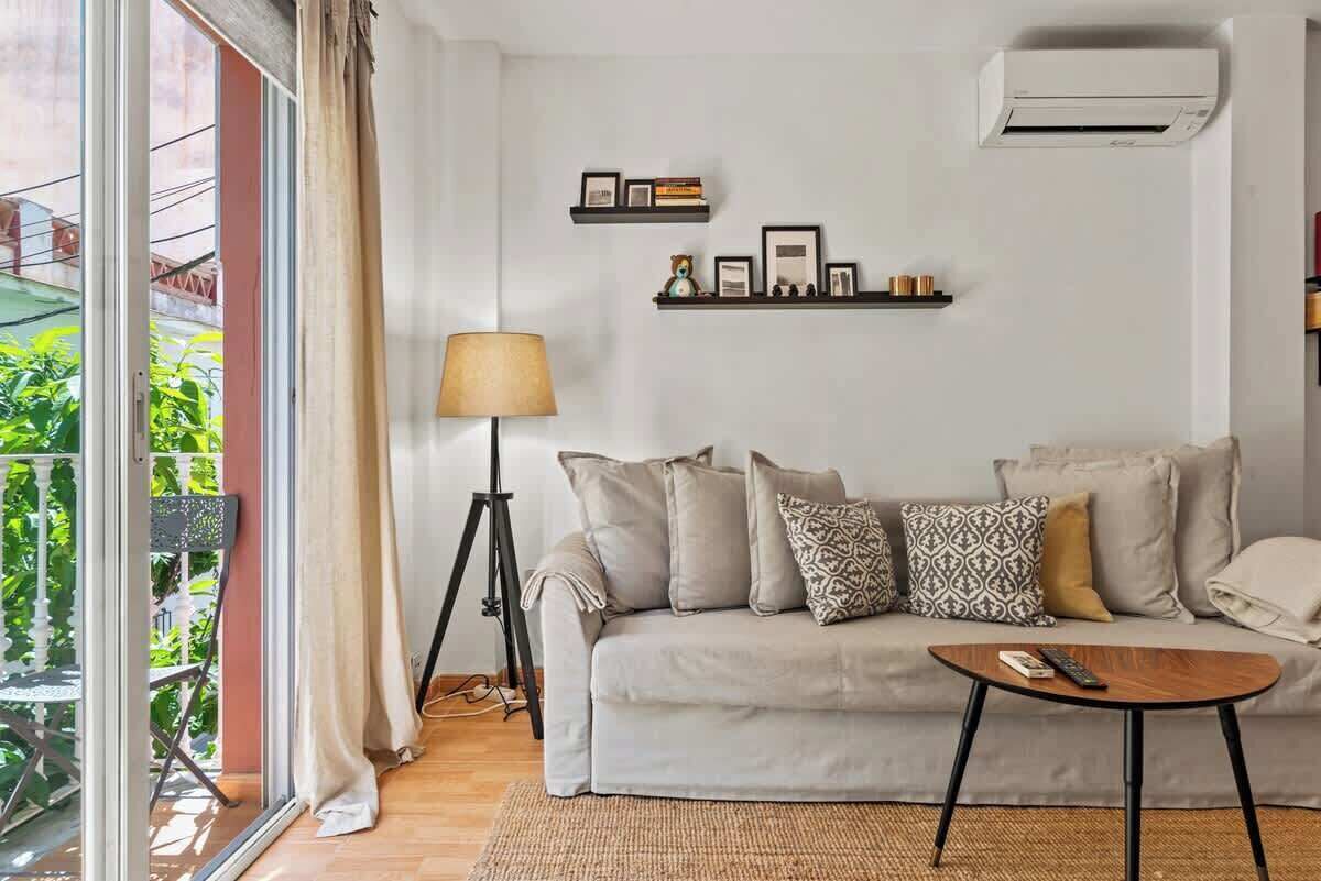 Een zithoek met een bank, salontafel, lamp en een balkon met planten.