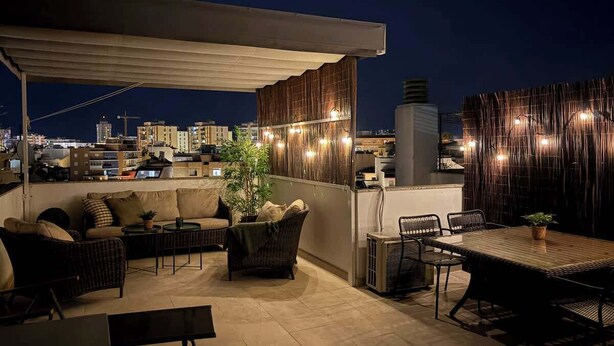 A rooftop terrace with outdoor seating, a dining area, and a view of the city skyline at night. - Stunning Rooftop Condo with Sea Views in Fuengirola (Fuengirola)
