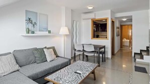 A modern living room with a grey sofa, a patterned coffee table, and a dining area with chairs and a table. - Stunning Rooftop Condo with Sea Views in Fuengirola (Fuengirola)