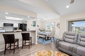 A modern kitchen with a dining area, a gray sofa, and a large window. - Gaetano's Getaway by Miss Kitty’s (Rockport)
