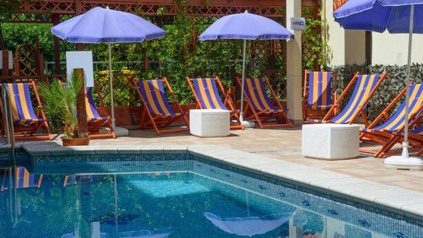 Une piscine avec des chaises longues et des parasols.