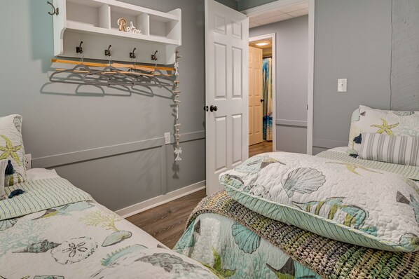 A bedroom with two beds, a wardrobe, and a door leading to another room.
