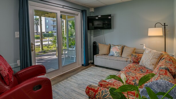 A living room with a sofa, a red massage chair, a TV, and a lamp. - 'Below Deck' Beach House: Walk to the Ocean! (Surfside Beach)